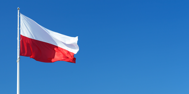 In the background the blue sky. In the front on the left, the polish flag on a mast
