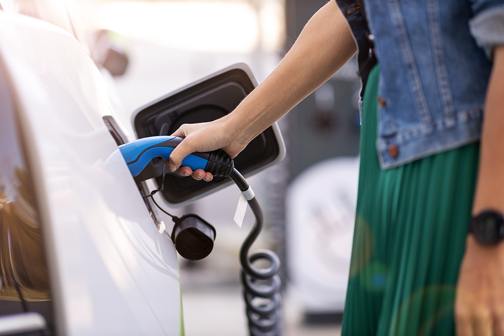 PHEV being charged by a person a PHEV being charged by a person viewed from the side
